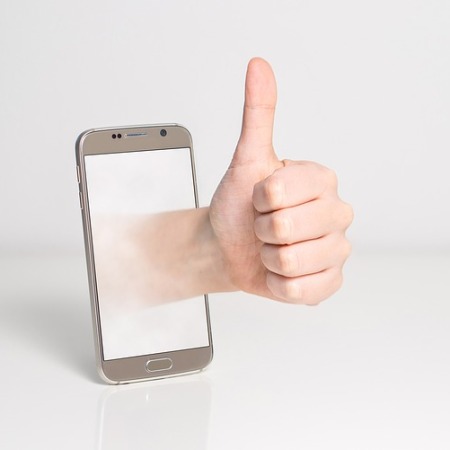 Thumbs up coming out of a mobile phone